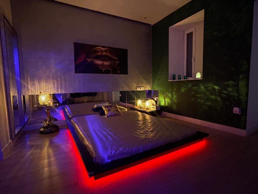Dormitorio moderno con cama iluminada y luces ambientales