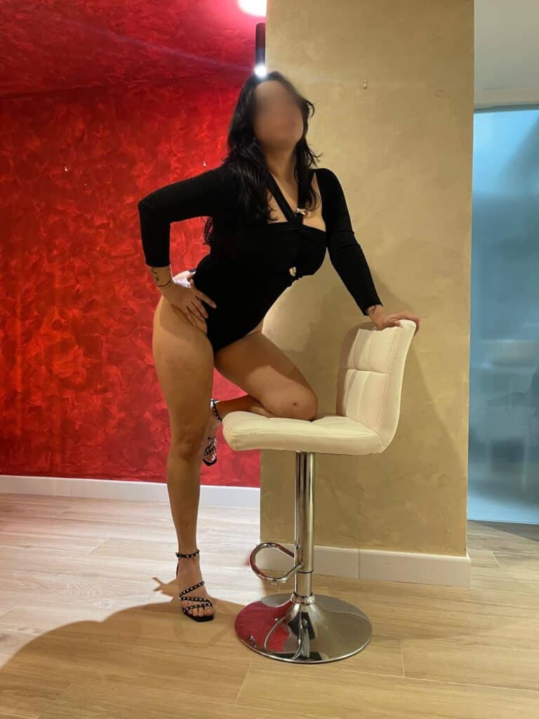 Mujer posando junto a una silla moderna